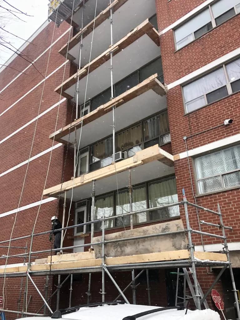 Balcony slab and railing repair under way on a brick high-rise