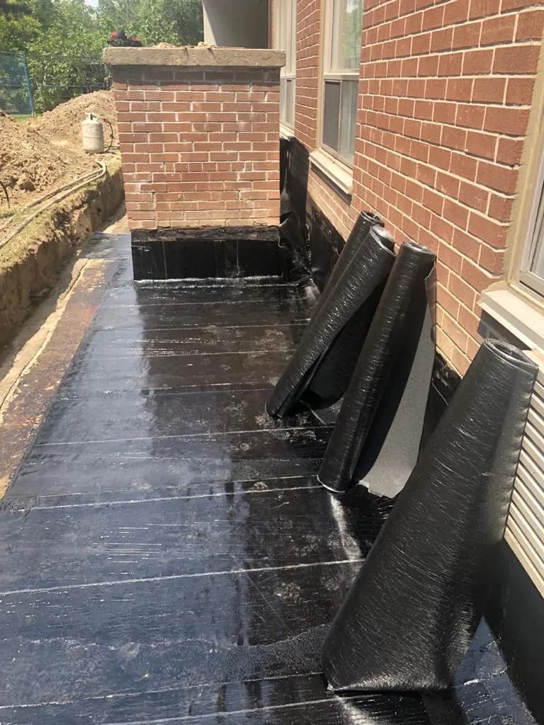 Waterproofing membrane applied along a building foundation wall